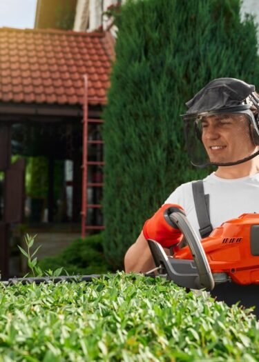 Hedge-Trimming-Service Professional landscaper trimming a hedge with a hedge trimmer in Naples, FL